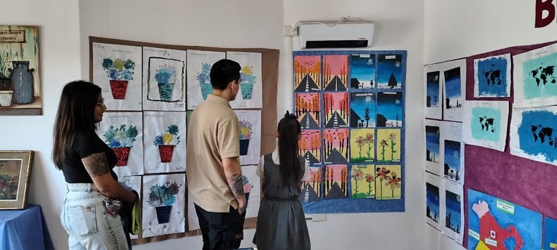 Familias recorren la muestra de arte con dibujos y pinturas de las y los estudiantes colgados en las paredes