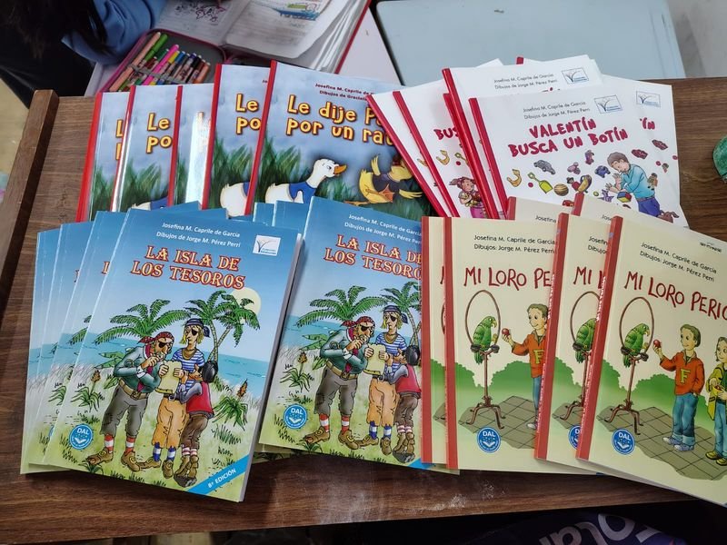 Libros del taller literario sobre una mesa del aula: «La isla de los tesoros», «Mi loro Perico», «Valentín busca un botín» y «Le dije Pato por un ratón»