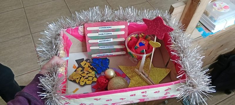 Caja decorada del Taller Navideño con guirnalda plateada, estrellas de goma eva, adornos y los nombres «Consejero, Dios fuerte, Admirable, Padre eterno, Príncipe de paz»